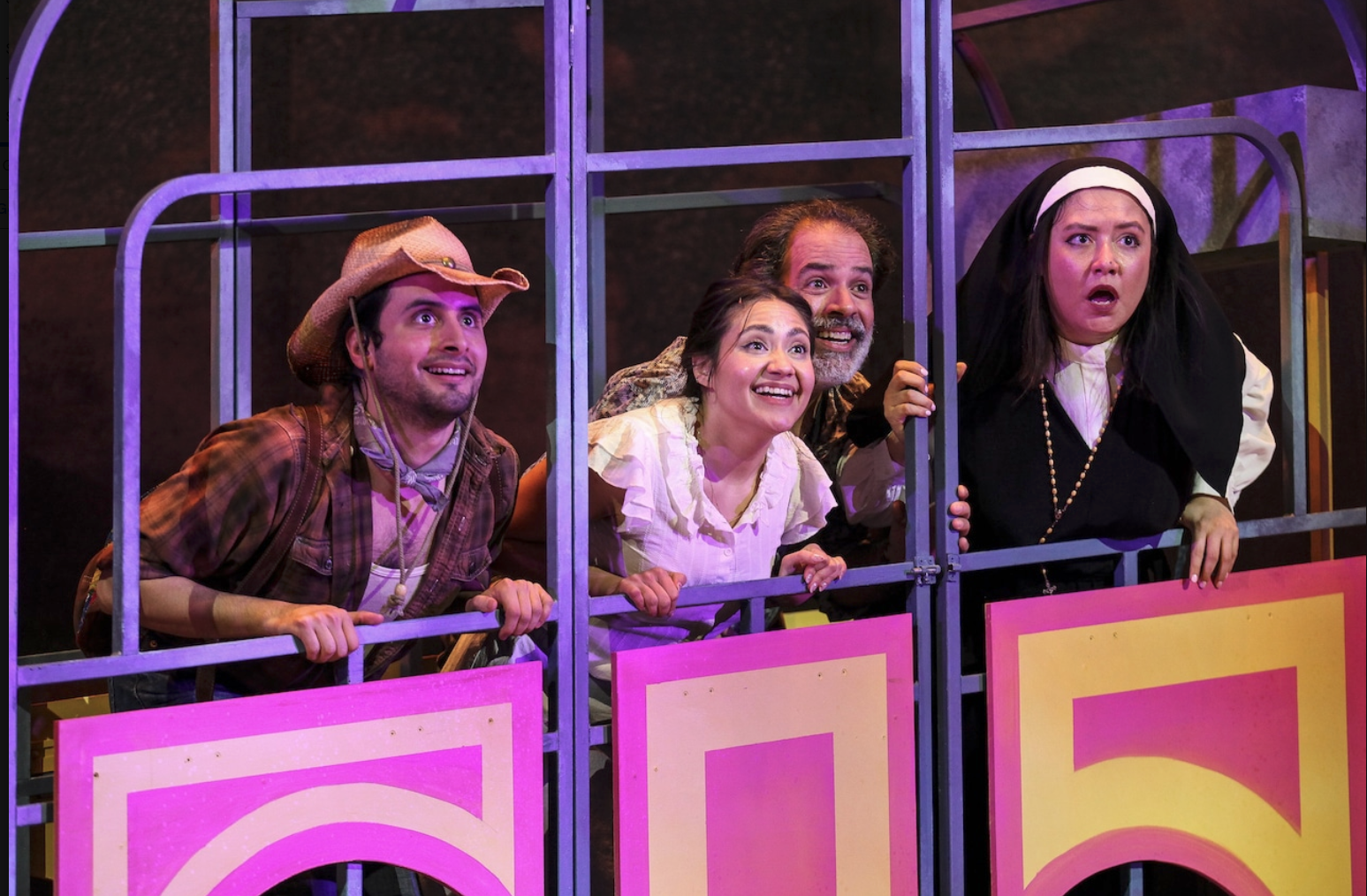 Ensemble cast peering through a purple window set piece on stage